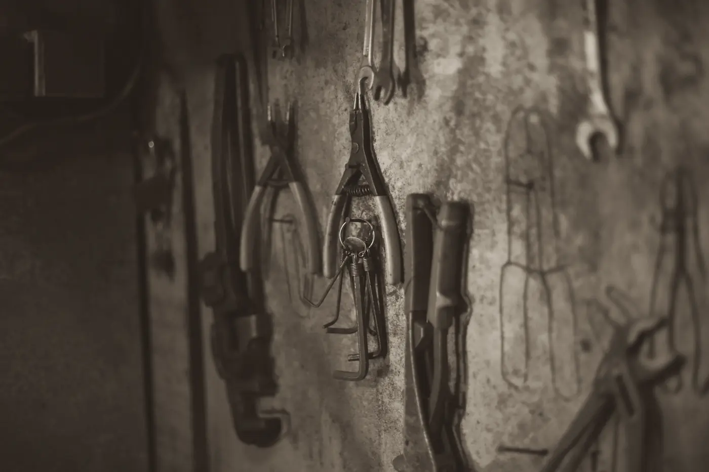 Pliers and wrenches hanging on a worn workshop wall
